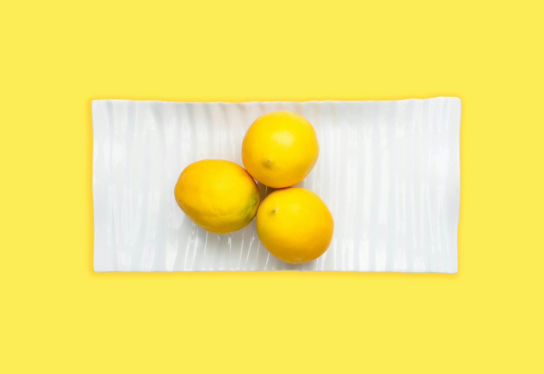 Yellow silicone vibrator surrounded by fresh produce on a bright background