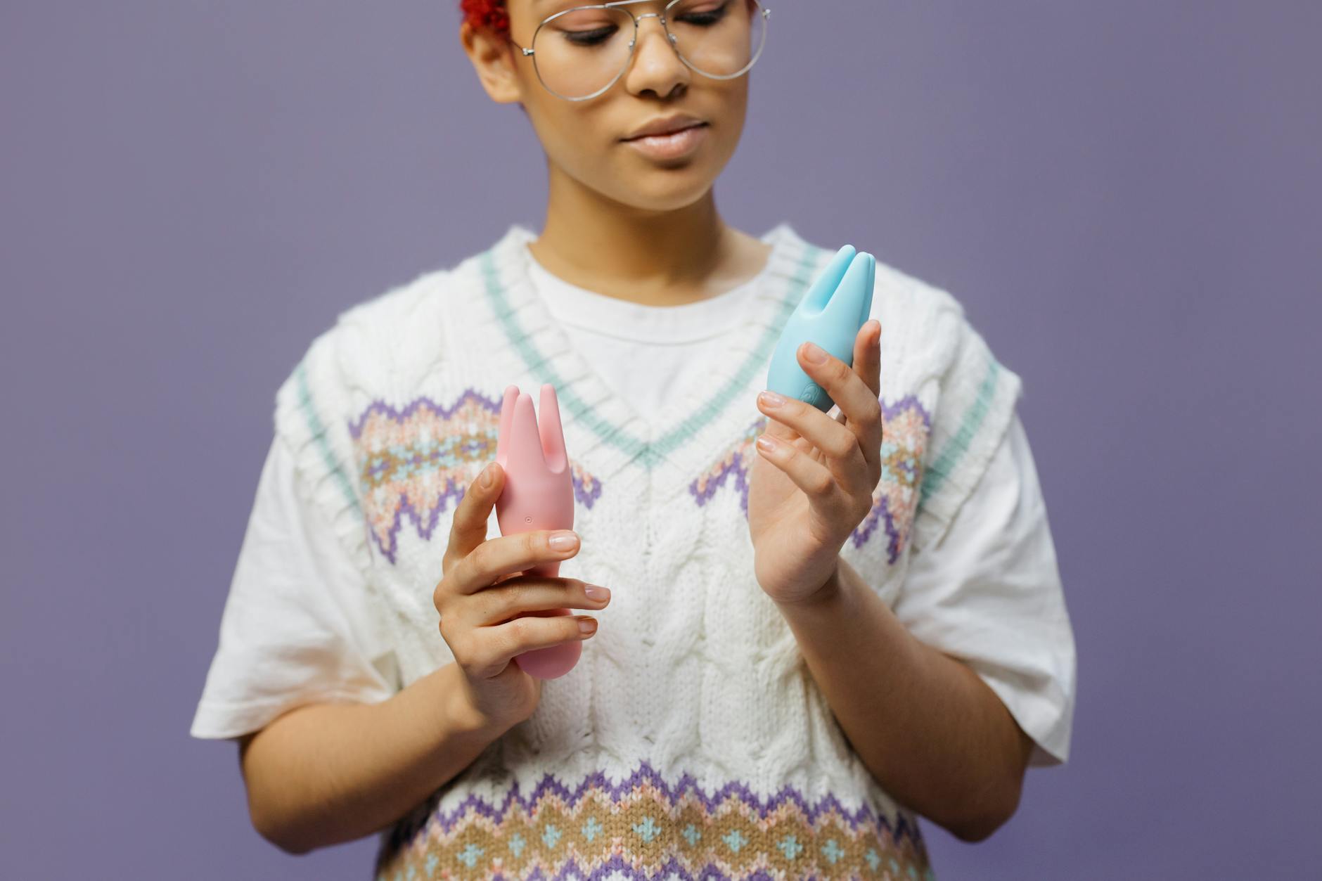 Mujer sosteniendo vibradores de silicona rosa y azul con expresión reflexiva