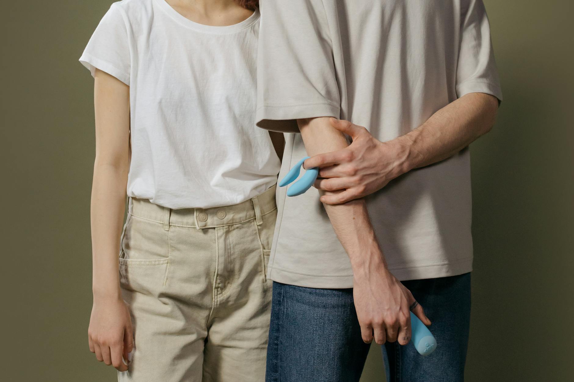 Una pareja joven de pie juntos sosteniendo un vibrador azul, simbolizando la intimidad moderna